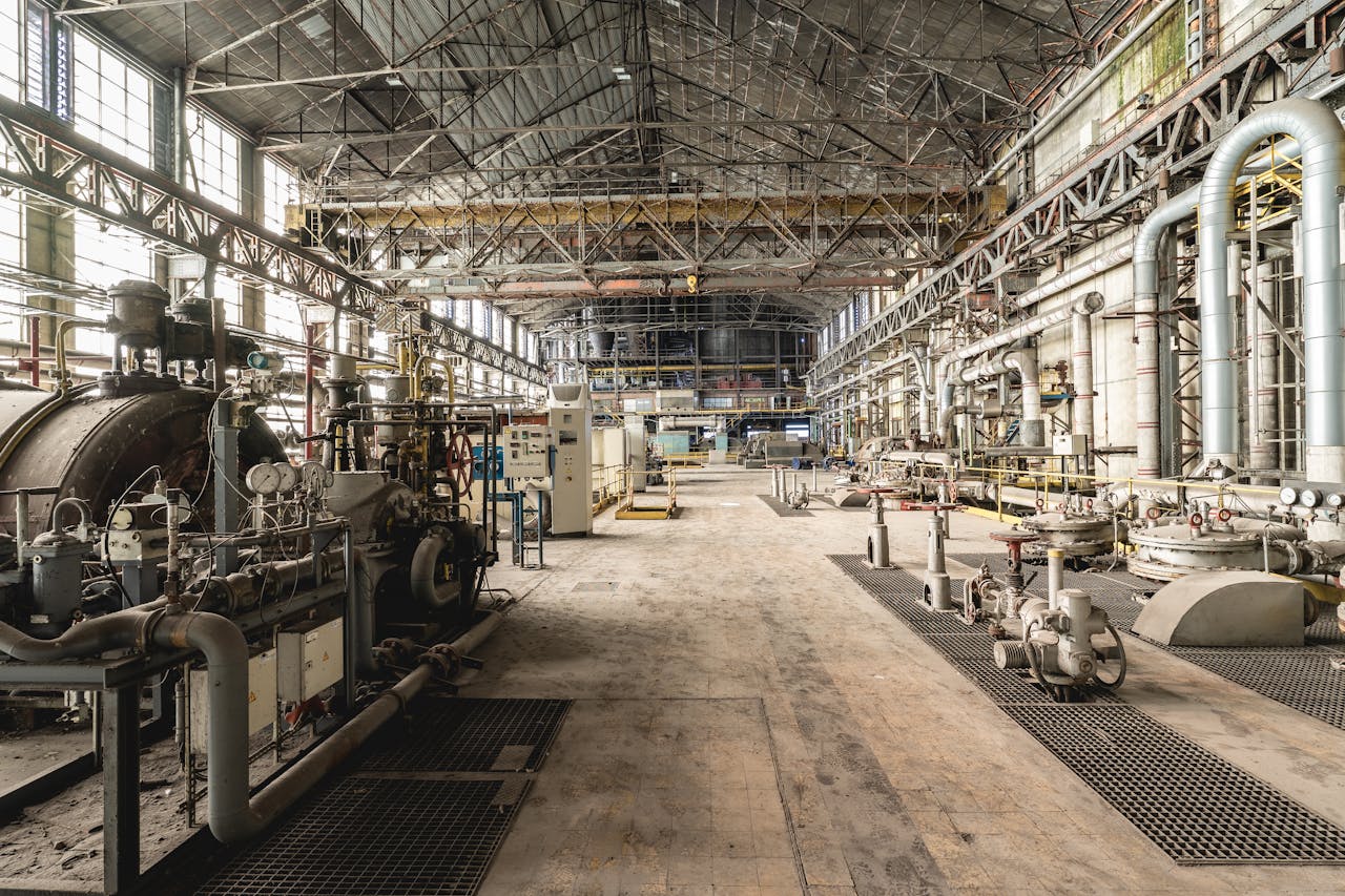 about-us Spacious industrial warehouse interior featuring machinery and network of pipes.